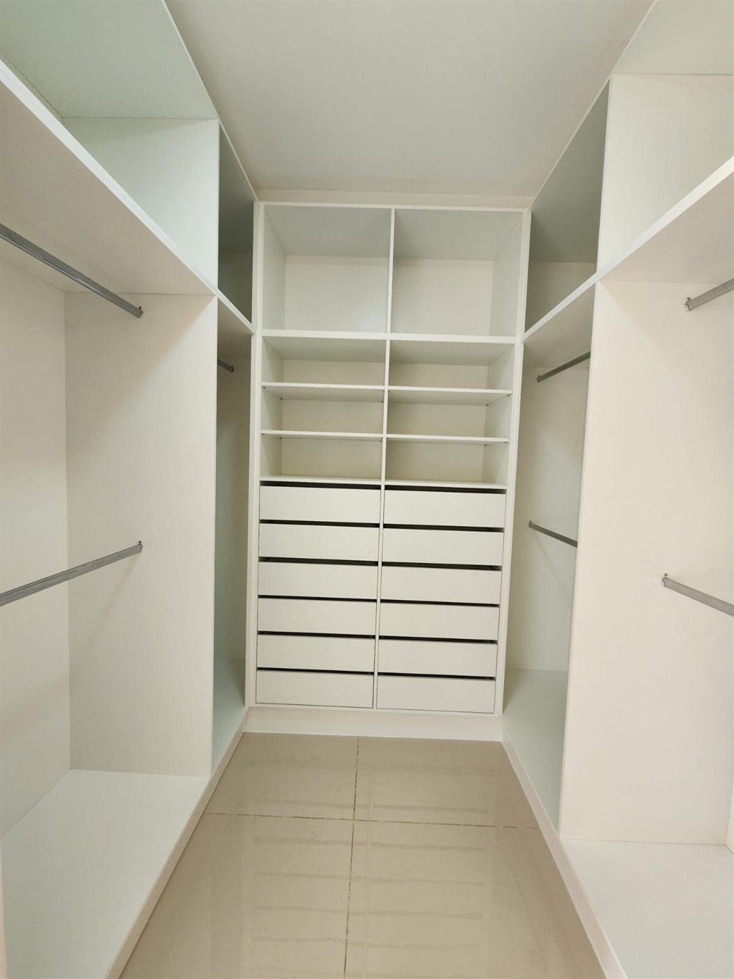 Closet planejado branco com gaveteiro e cabideiros