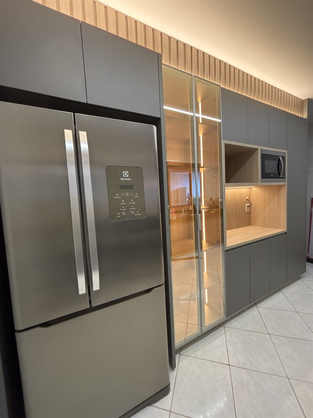 Cozinha planejada cinza com nicho iluminado e geladeira inox embutida